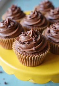 A vibrant display of mudslide cupcakes beautifully decorated with rich chocolate frosting, sprinkled with chocolate shavings, and arranged on a colorful cake stand. The background is festive and inviting, perfect for a celebration.